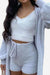 Woman wearing cozy white Cloud Soft 4-Piece lounge set with cardigan, crop top, and shorts made of plush fabric